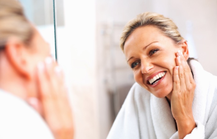 woman looking at glowing skin in mirror